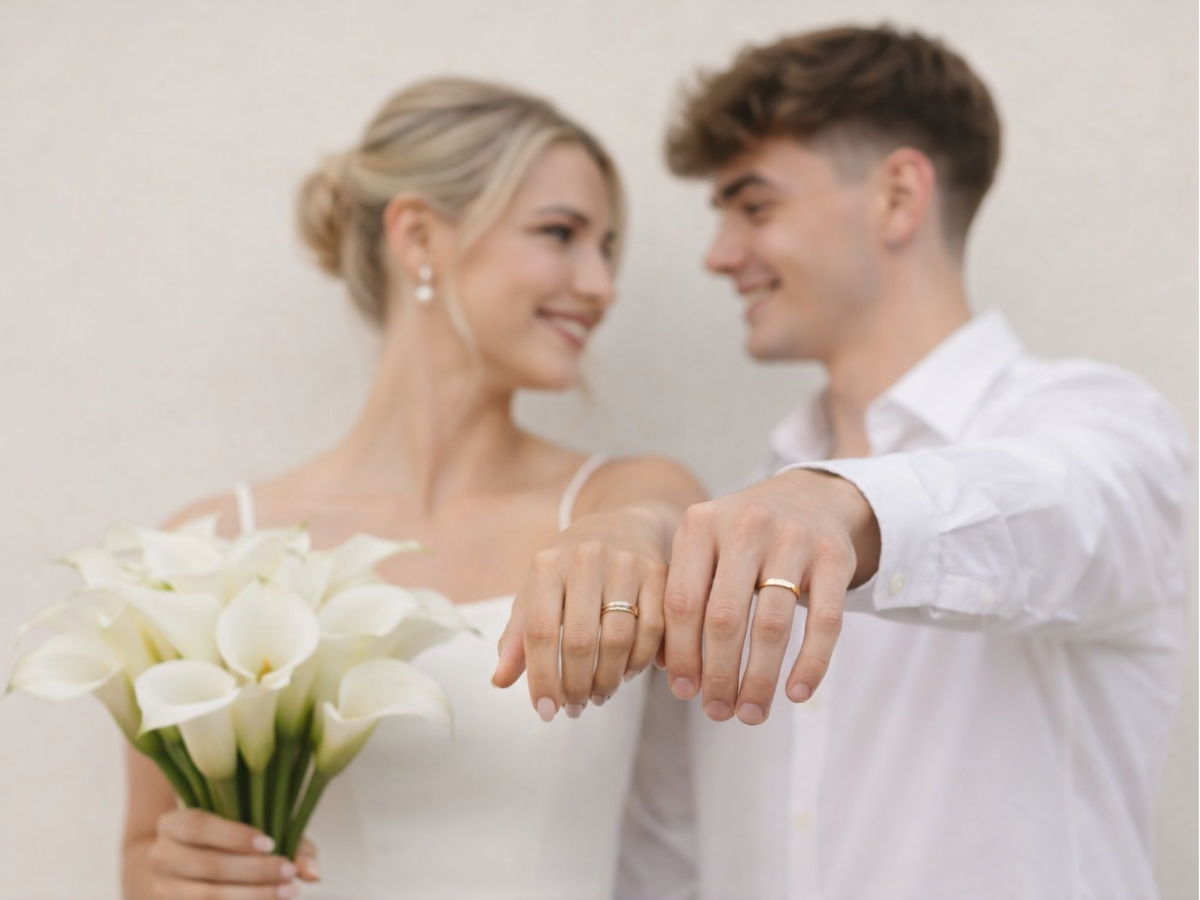 Casamento civil representado por casal de mãos estendidas mostrando alianças de forma discreta.