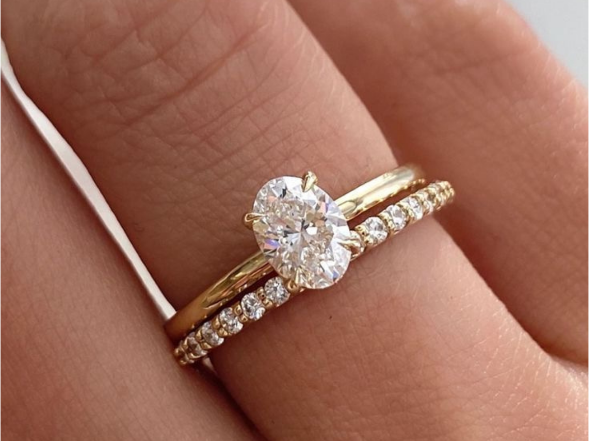 Anel de noivado com diamante central acompanhado de meia aliança cravejada.