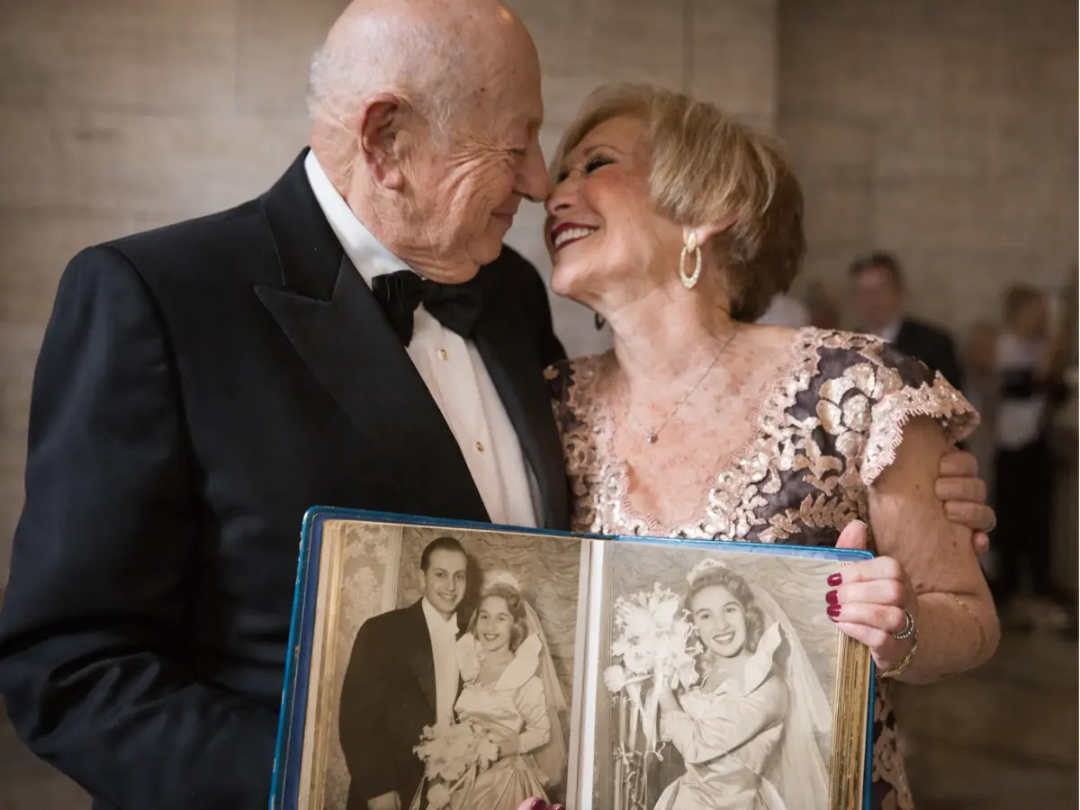 Casal celebrando 50 anos segurando álbum de fotos antigas