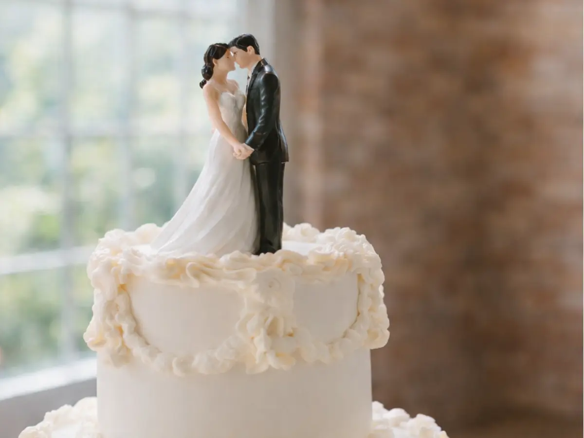 Topo de bolo com noivinhos clássicos sobre bolo branco de casamento.