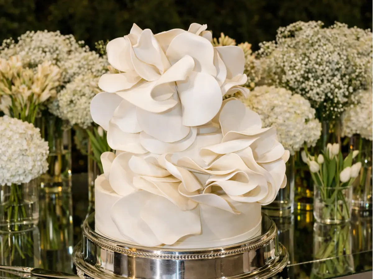 Bolo de casamento escultural com camadas de pétalas brancas em decoração artística e sofisticada.