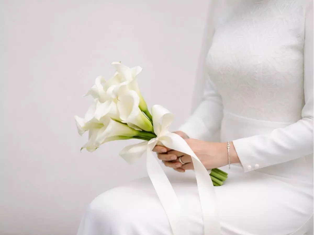 Buquê minimalista de copos-de-leite brancos com fita longa em ambiente clean