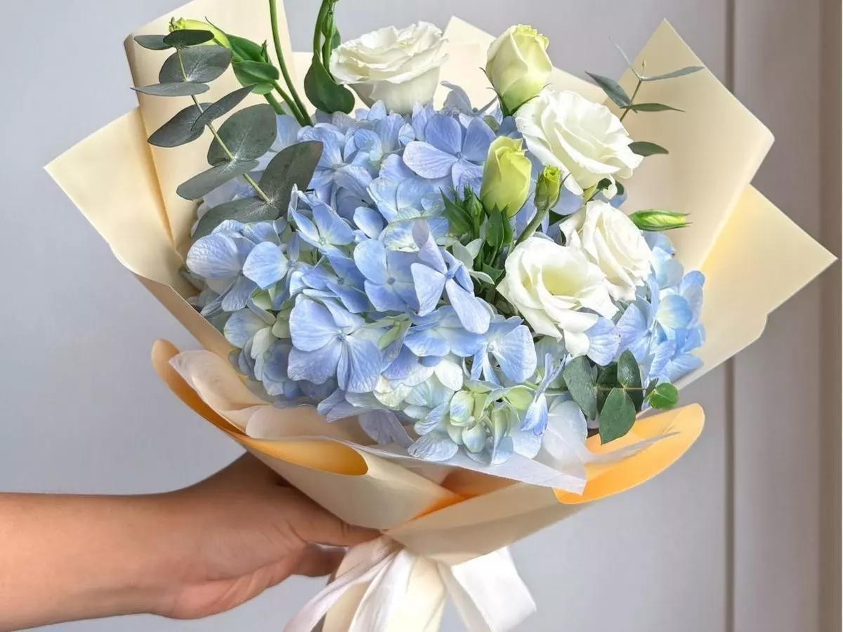 Buquê de hortênsias azuis com rosas brancas e folhagens verdes