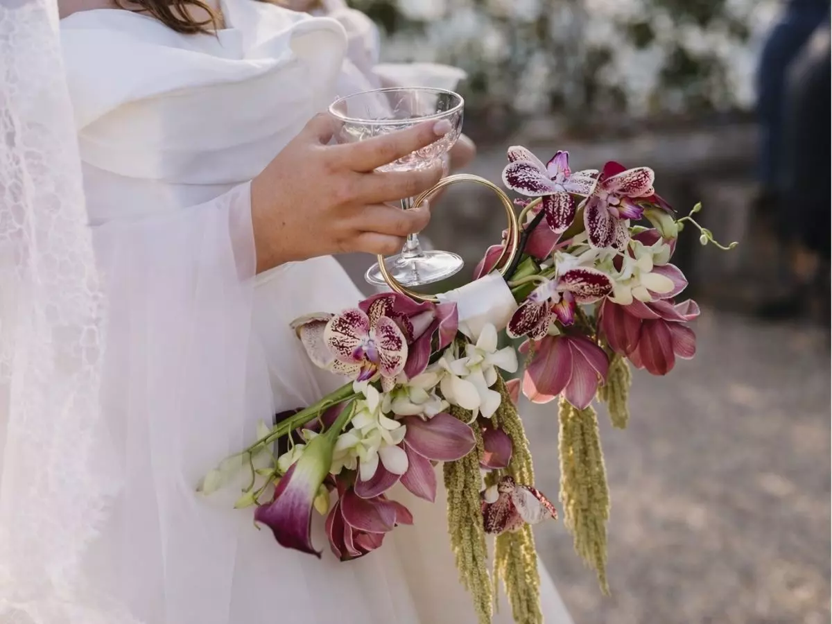 Buquê de noiva com orquídeas em cascata e design moderno segurado pela noiva.