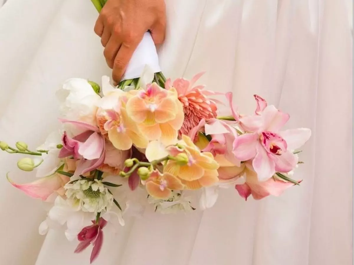 Buquê de noiva com orquídeas em tons suaves e formato horizontal elegante.