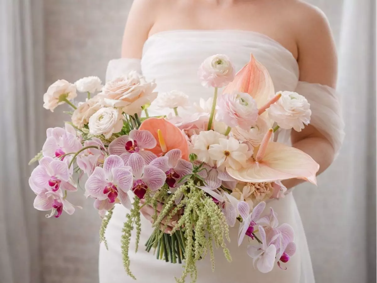 Buquê de noiva em tons rosados com orquídeas, antúrios e flores delicadas em composição elegante.