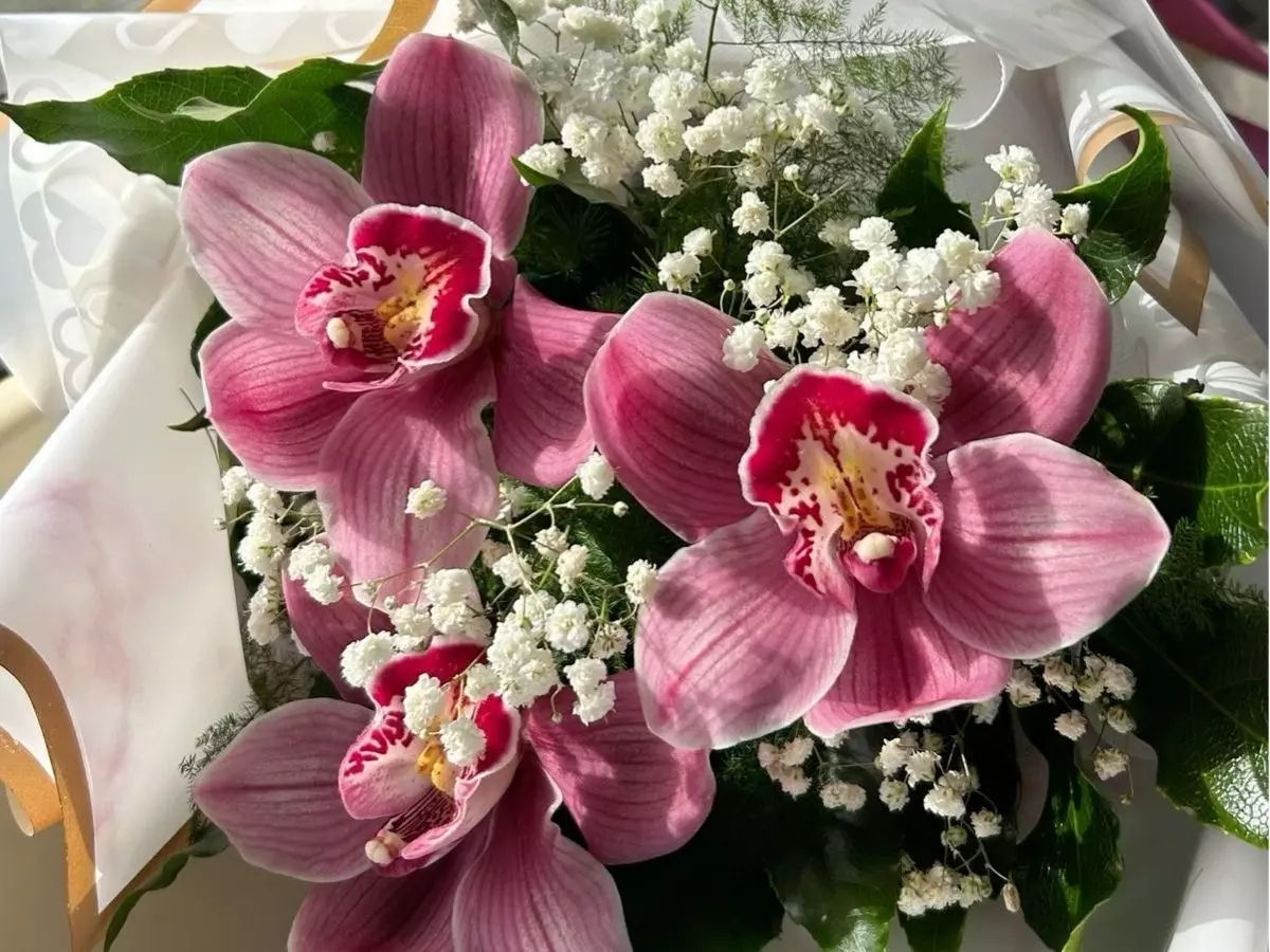 Arranjo com orquídeas rosas e flores brancas delicadas