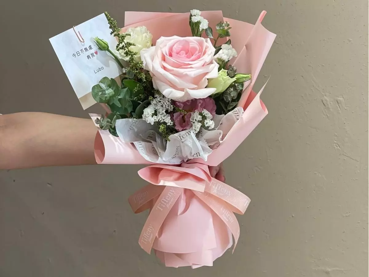 Buquê rosa claro com rosa central em destaque e folhagens delicadas