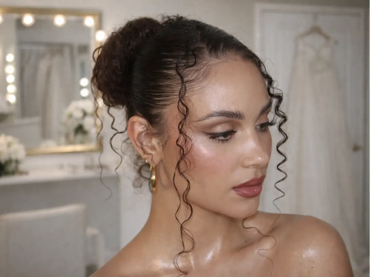 Penteado de madrinha com coque alto e fios cacheados soltos valorizando a textura natural