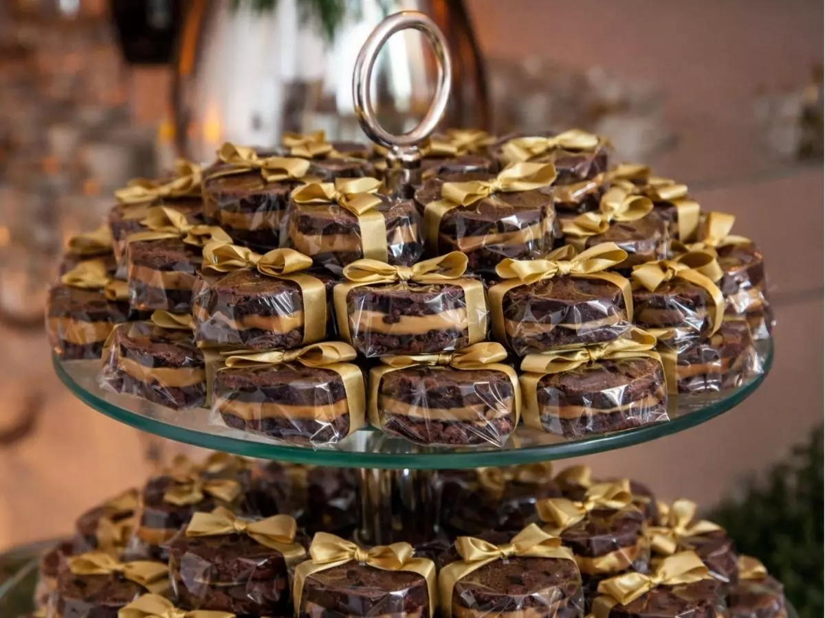 Pão de mel embalados individualmente com laço dourado em bandeja de vidro