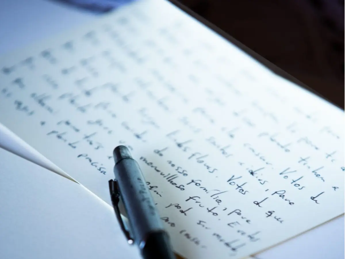 Mãos escrevendo mensagem de casamento personalizada em papel.