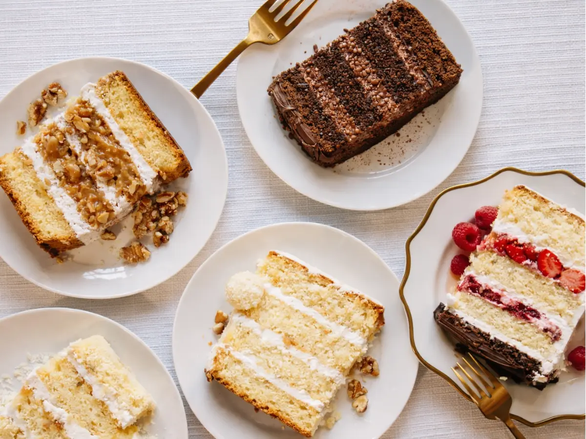 Fatias de bolo de casamento em diferentes sabores servidas em pratos claros com apresentação elegante.