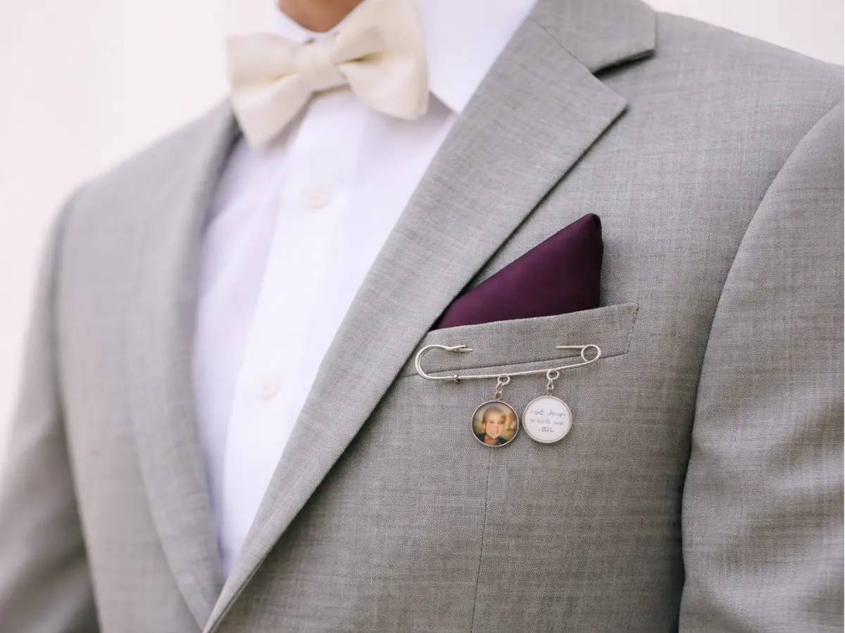 Lapela de noivo com alfinete decorativo e medalhas em terno cinza