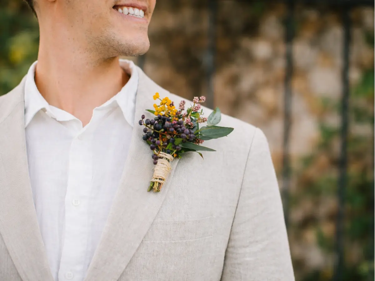 Lapela de noivo com folhagens verdes e pequenas frutas decorativas