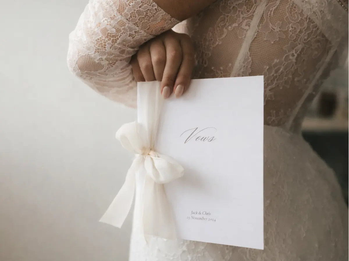 Detalhe de livro de votos de casamento com laço de tecido nas mãos da noiva