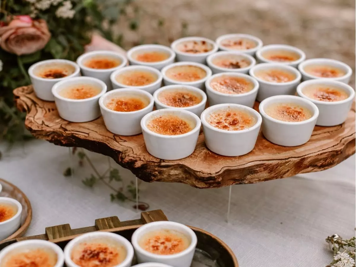 Mini crème brûlée servido em ramequins brancos sobre mesa rústica de casamento