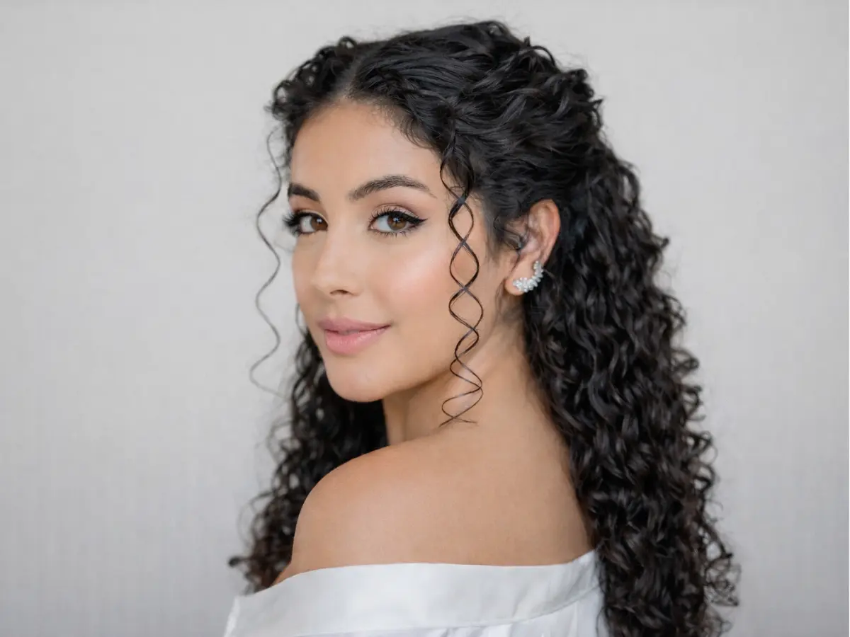 Noiva com cabelo cacheado meio preso e maquiagem suave em tons naturais