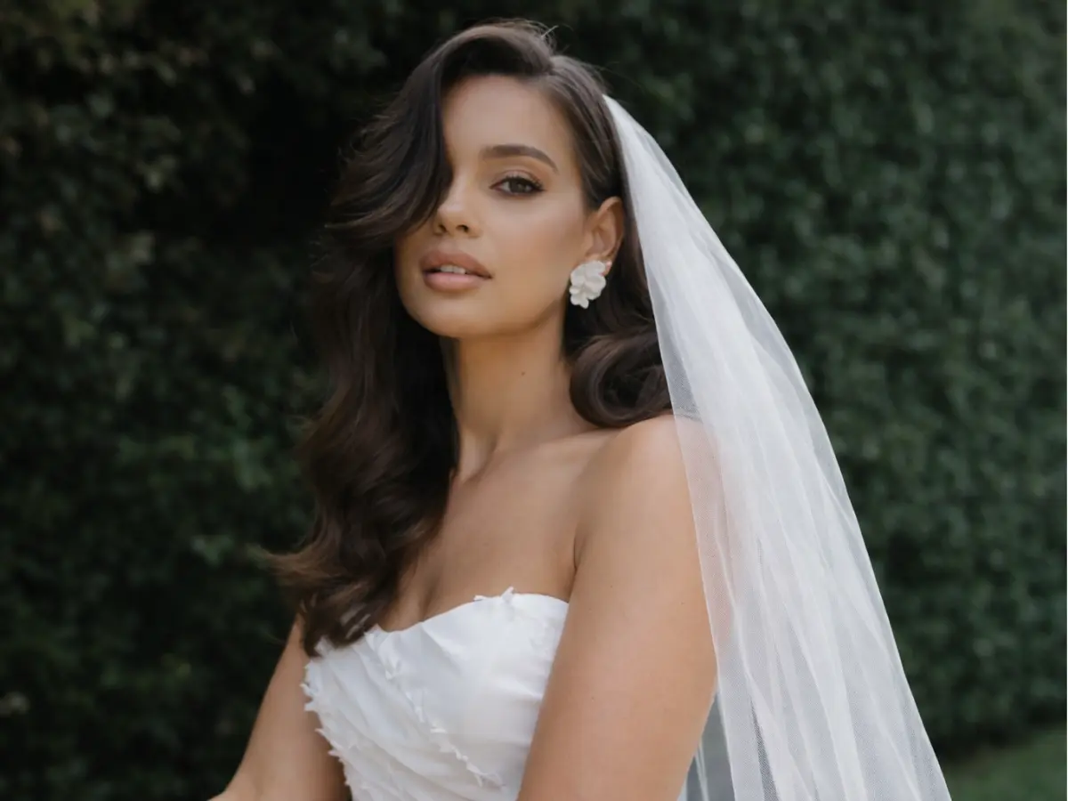 Noiva com véu lateral e cabelo solto em ondas suaves em ambiente externo
