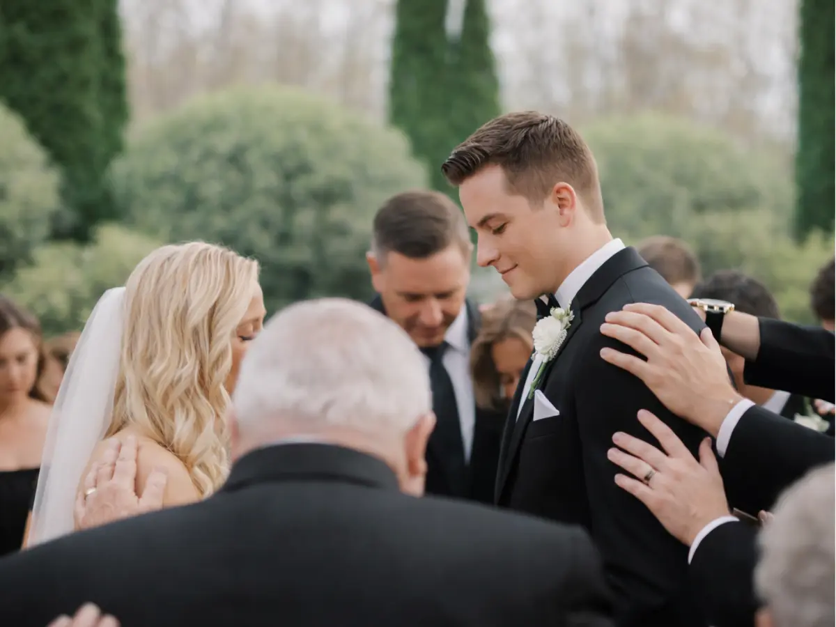 Noivos em círculo de oração com familiares e amigos durante a cerimônia ao ar livre