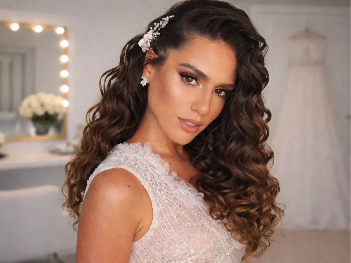 Noiva com cabelo solto cacheado, volume natural e aplicação lateral de acessórios