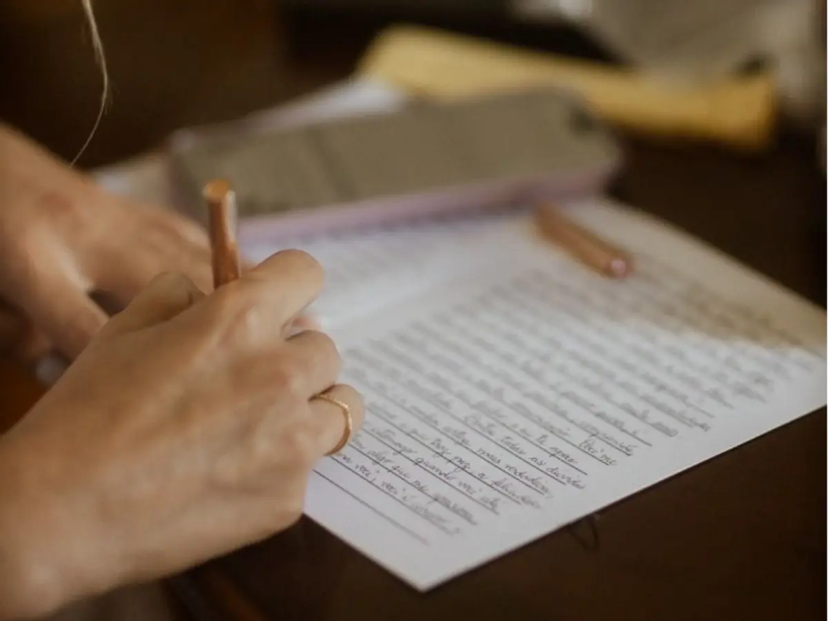 Pessoa escrevendo uma mensagem especial à mão em papel delicado.
