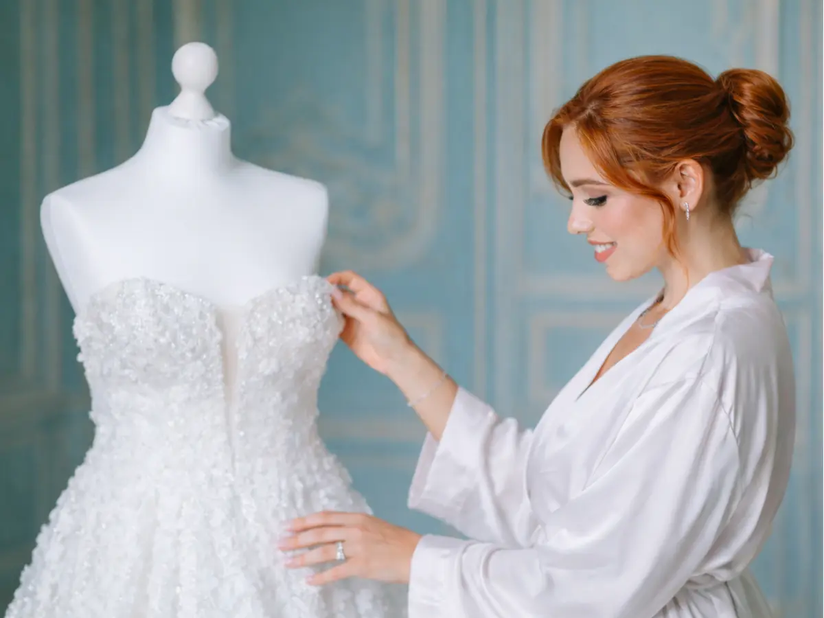 Noiva observando vestido de noiva tomara que caia com bordados delicados em manequim