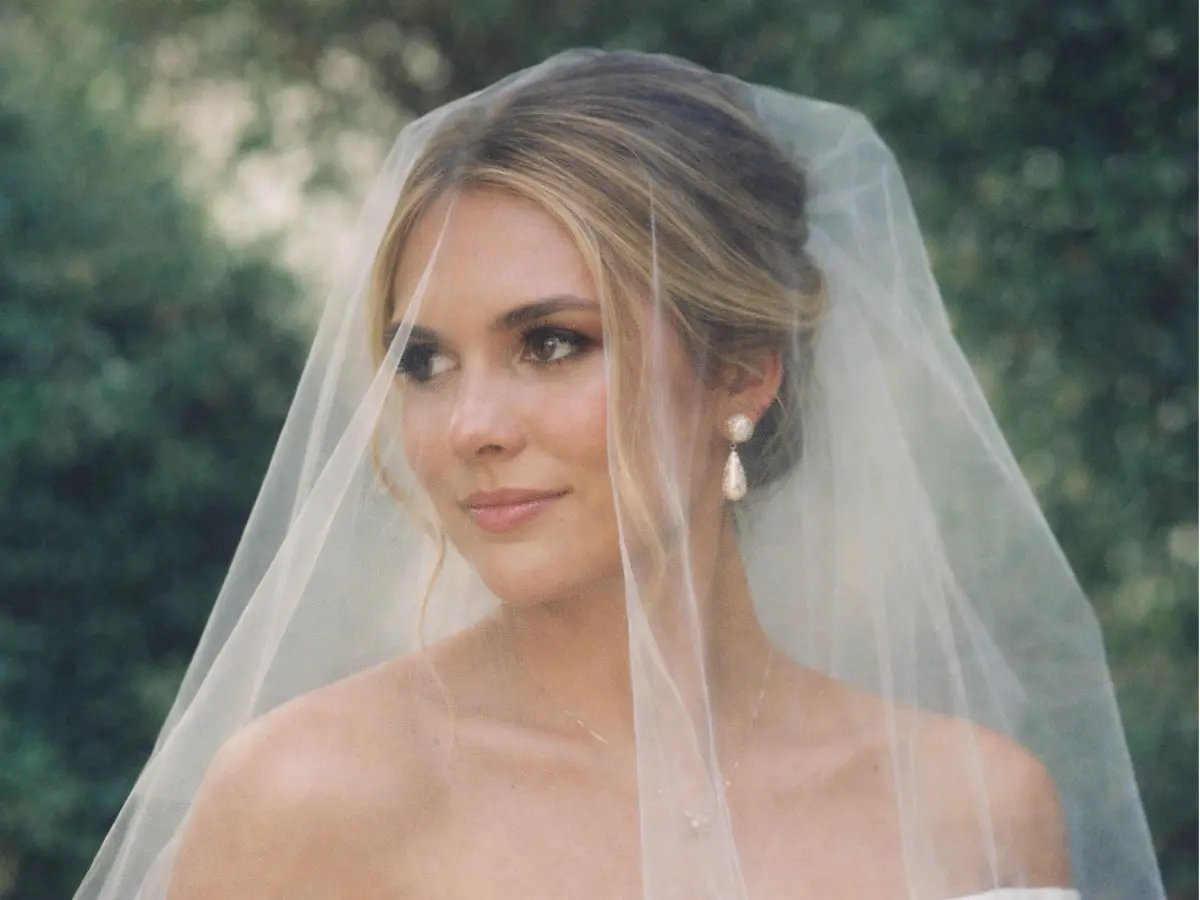 Noiva usando véu blusher curto cobrindo levemente o rosto.