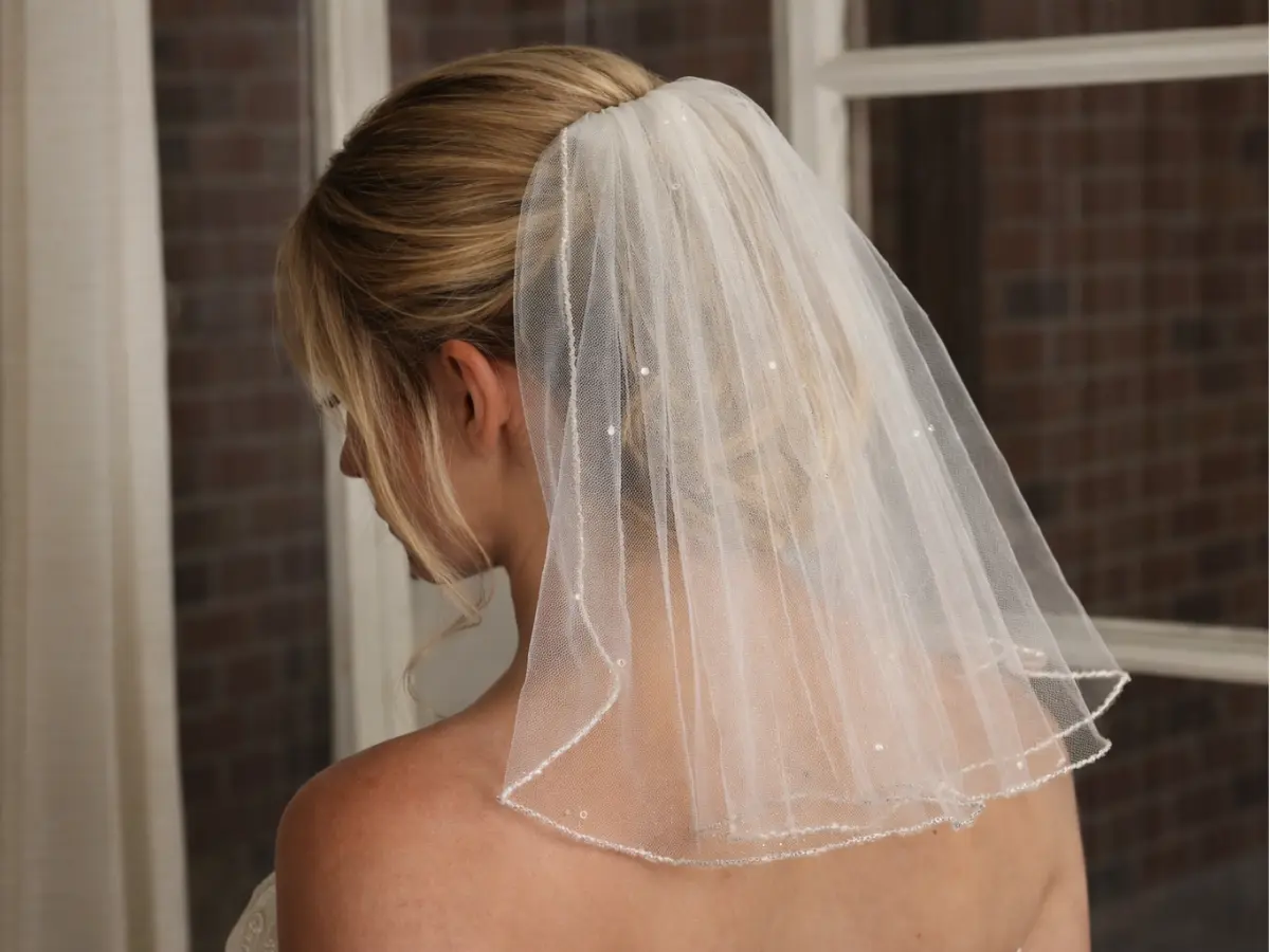 Noiva vista de costas usando véu curto na altura dos ombros.