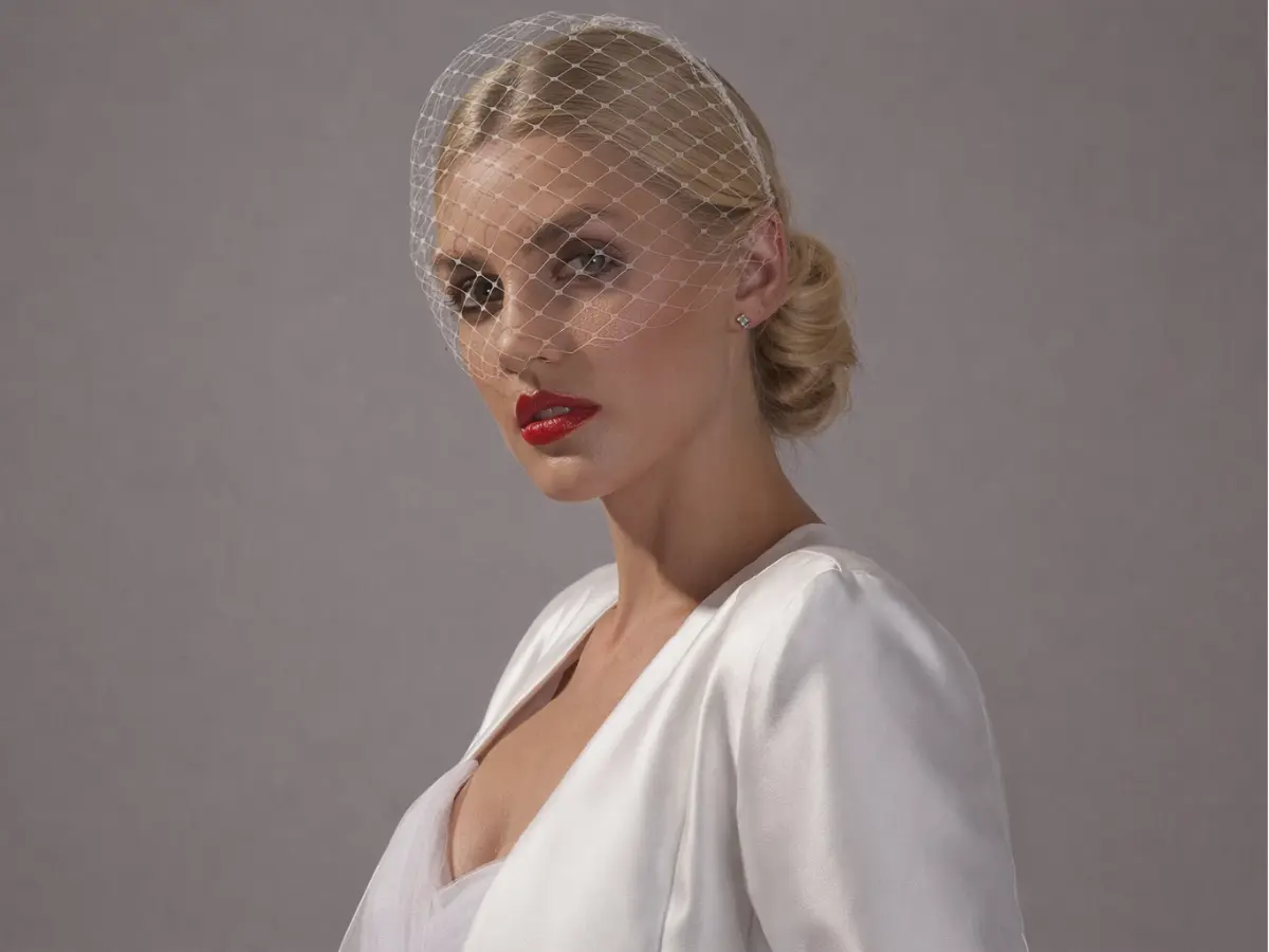 Noiva usando véu voilette curto em rede fina cobrindo parcialmente o rosto.